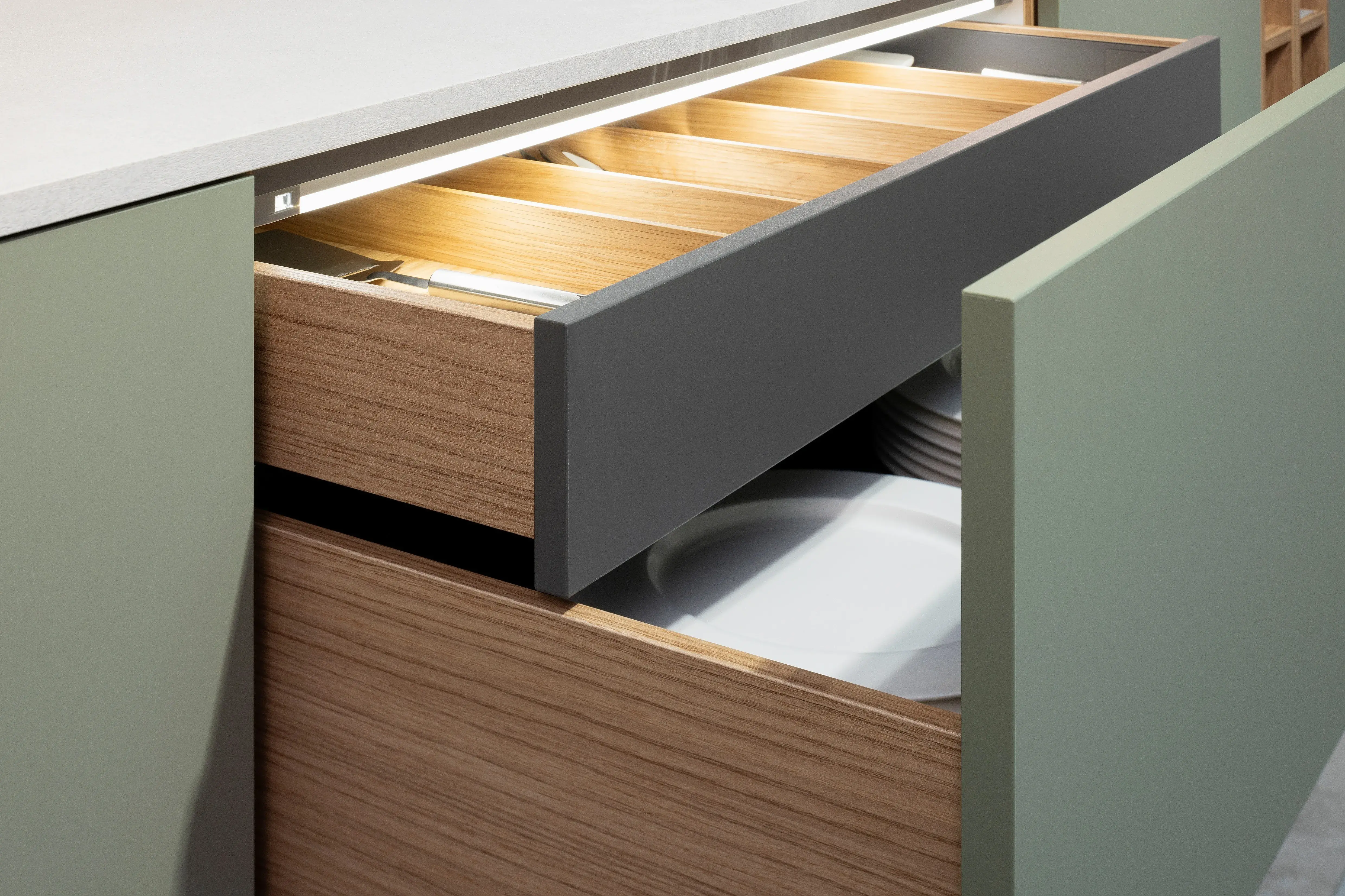 APL: 794 Beton Seidengrau NB (Xtra Ceramic) Korpus: 198 Eiche Sierra Front: Senso 495 Lack, Olive Premium matt Geräte: Neff Slide&Hide Armatur: Gessi  Spüle: Teka  Features: Trendfarbe Olive, Push to open, Tapete, neuer Schubkasten, Wandeinbau Backofen, beleuchtete Regale, beleuchtete Vitrinen, Weinflaschenregal, Schubkästen und Korpus in Eiche Sierra, Premium matte Oberfläche mit Antifingerprint, Nischenrückwand in Rillenoptik.