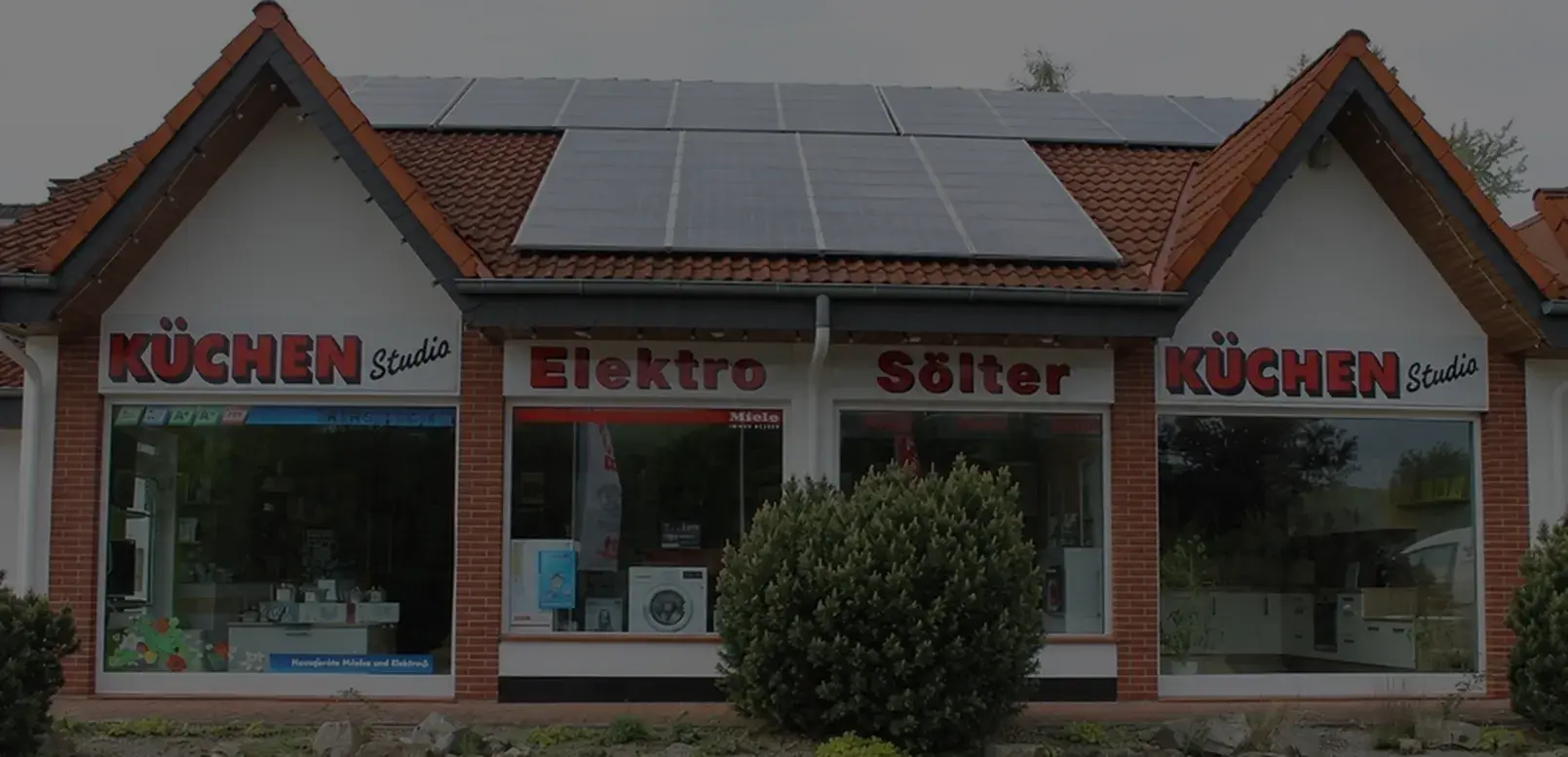 Geschäftsgebäude mit Solarpanelen auf dem Dach und Küchenstudio-Schildern.